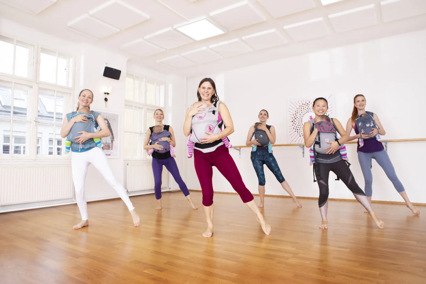 Mutter in Plank-Position auf der Yogamatte, ihr Baby krabbelt neben ihr