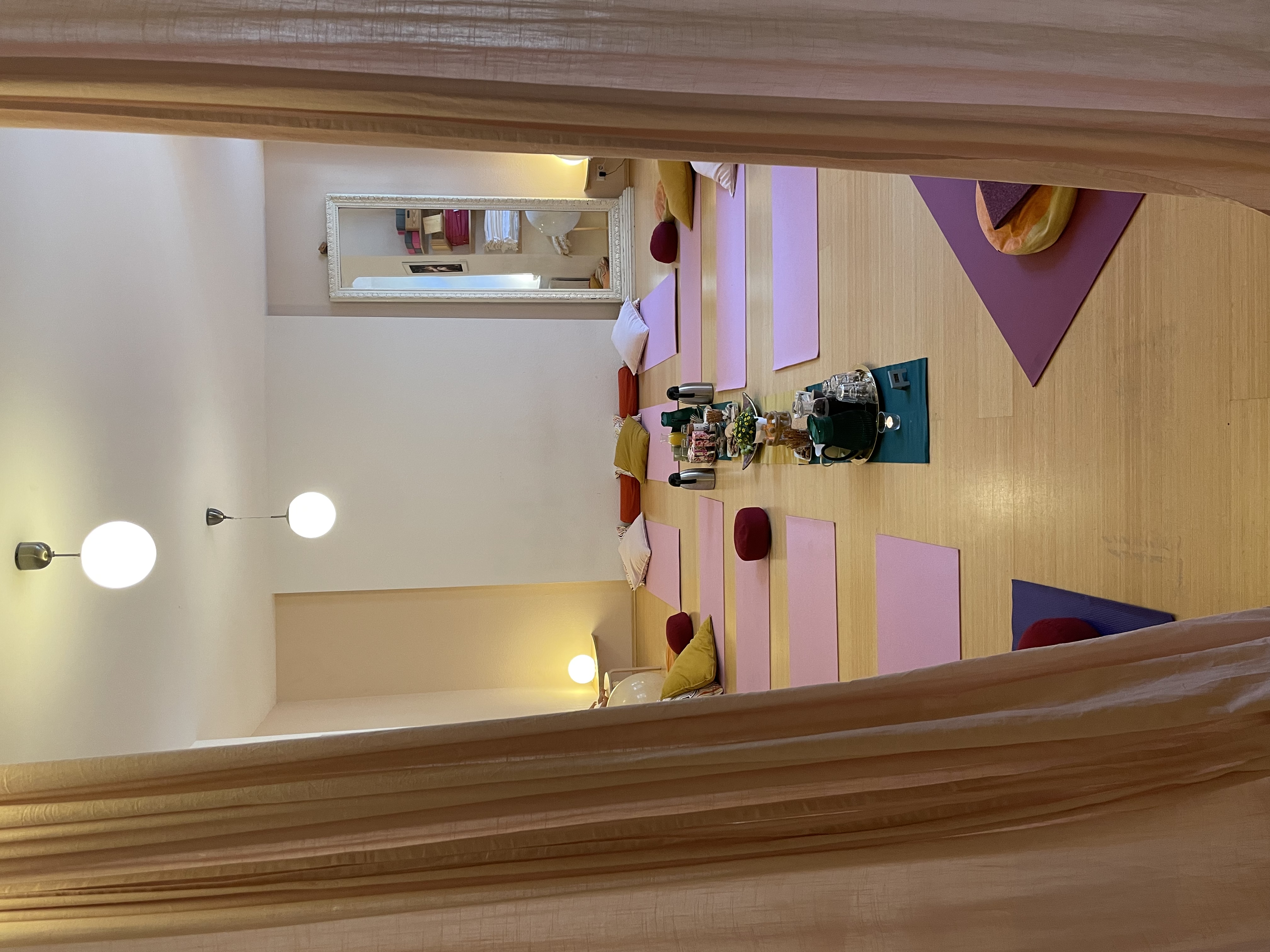 Kursraum mit rosa Yogamatten, vorbereitet für einen Kurs, durch Vorhang gesehen