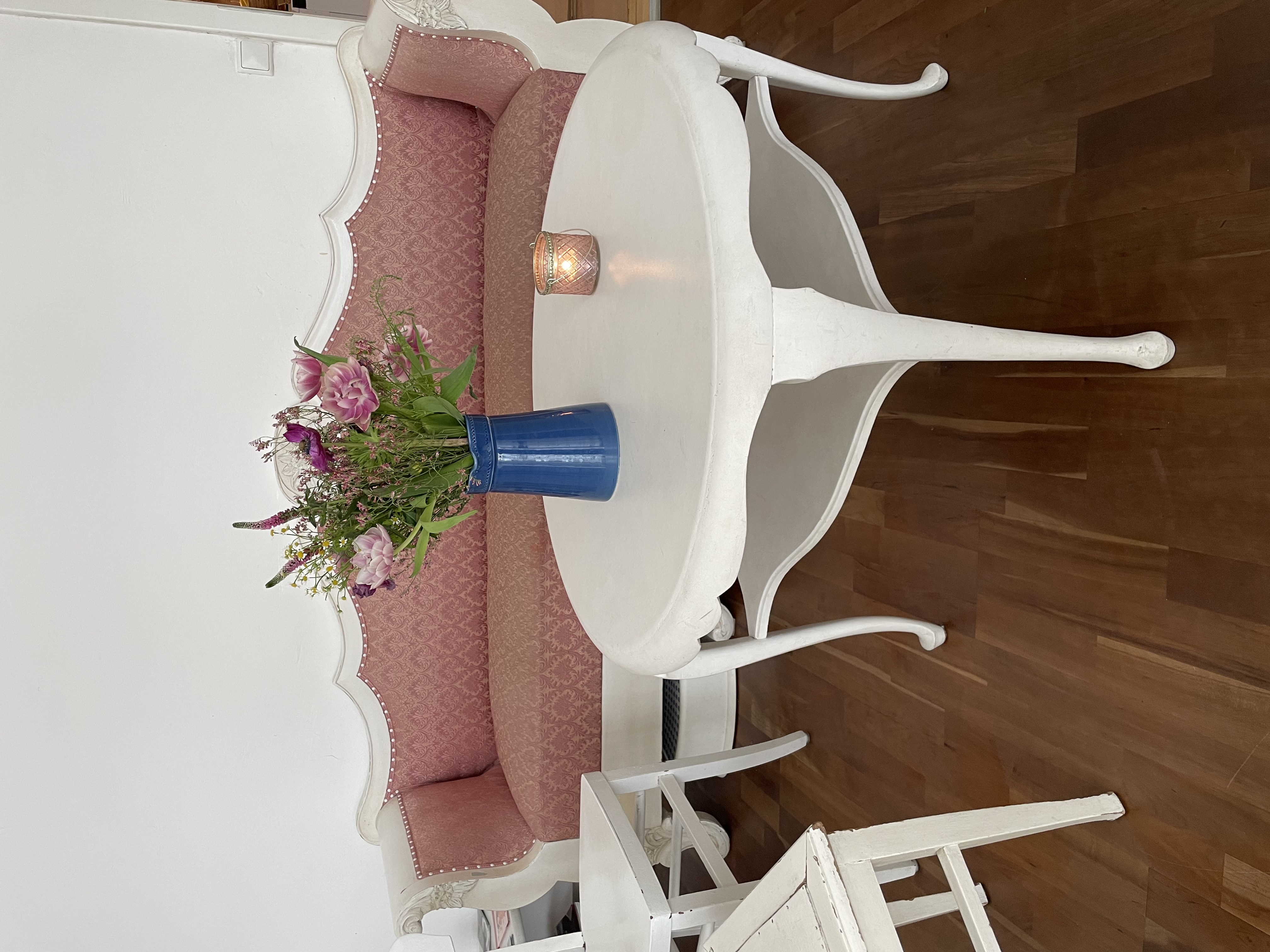 Antikes rosa Sofa mit Blumenstrauß auf rundem Tisch – Warteraum der Praxis Mittendrin