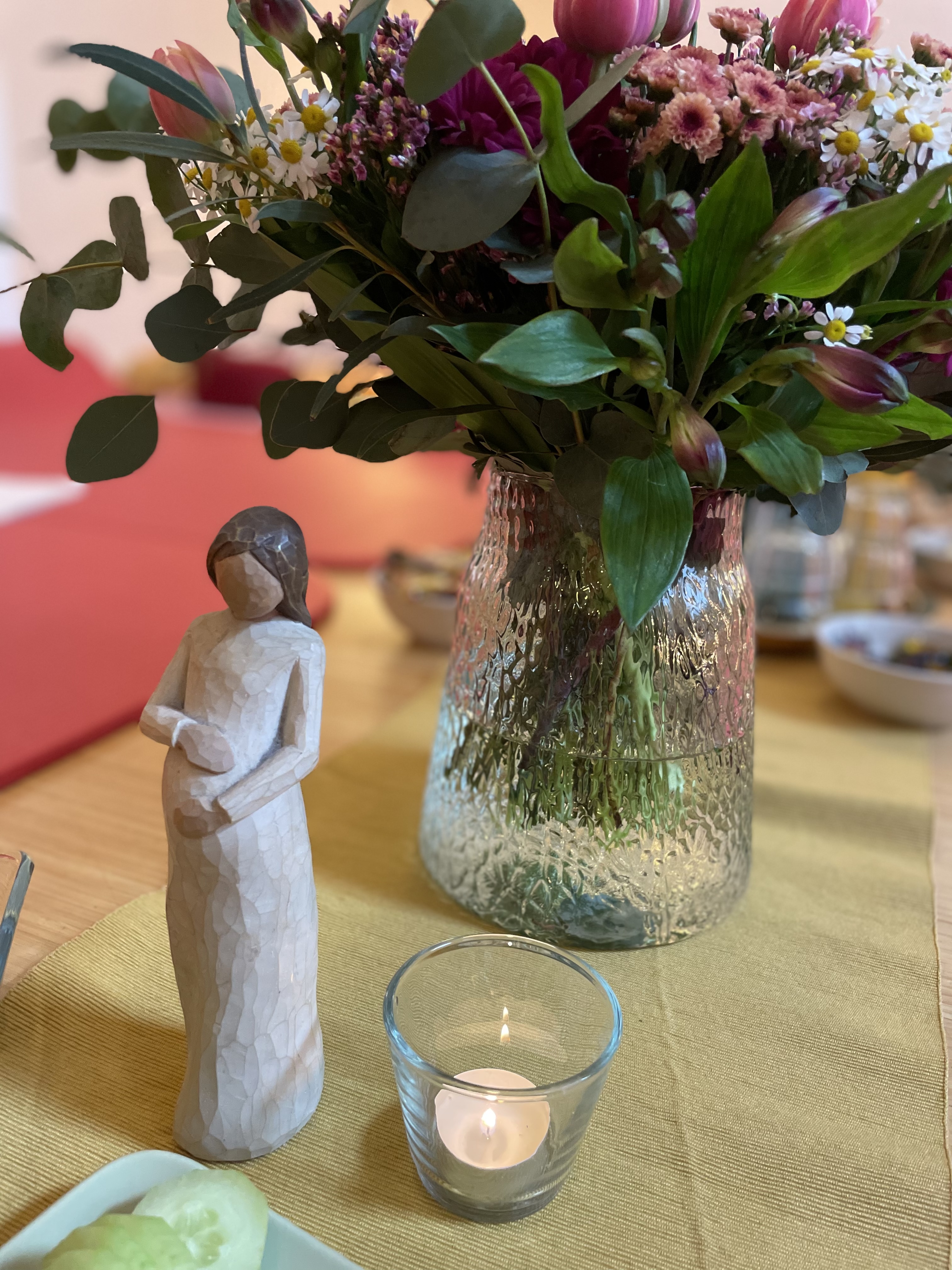 Willow-Tree Figur einer Schwangeren neben Blumenstrauß und Teelicht