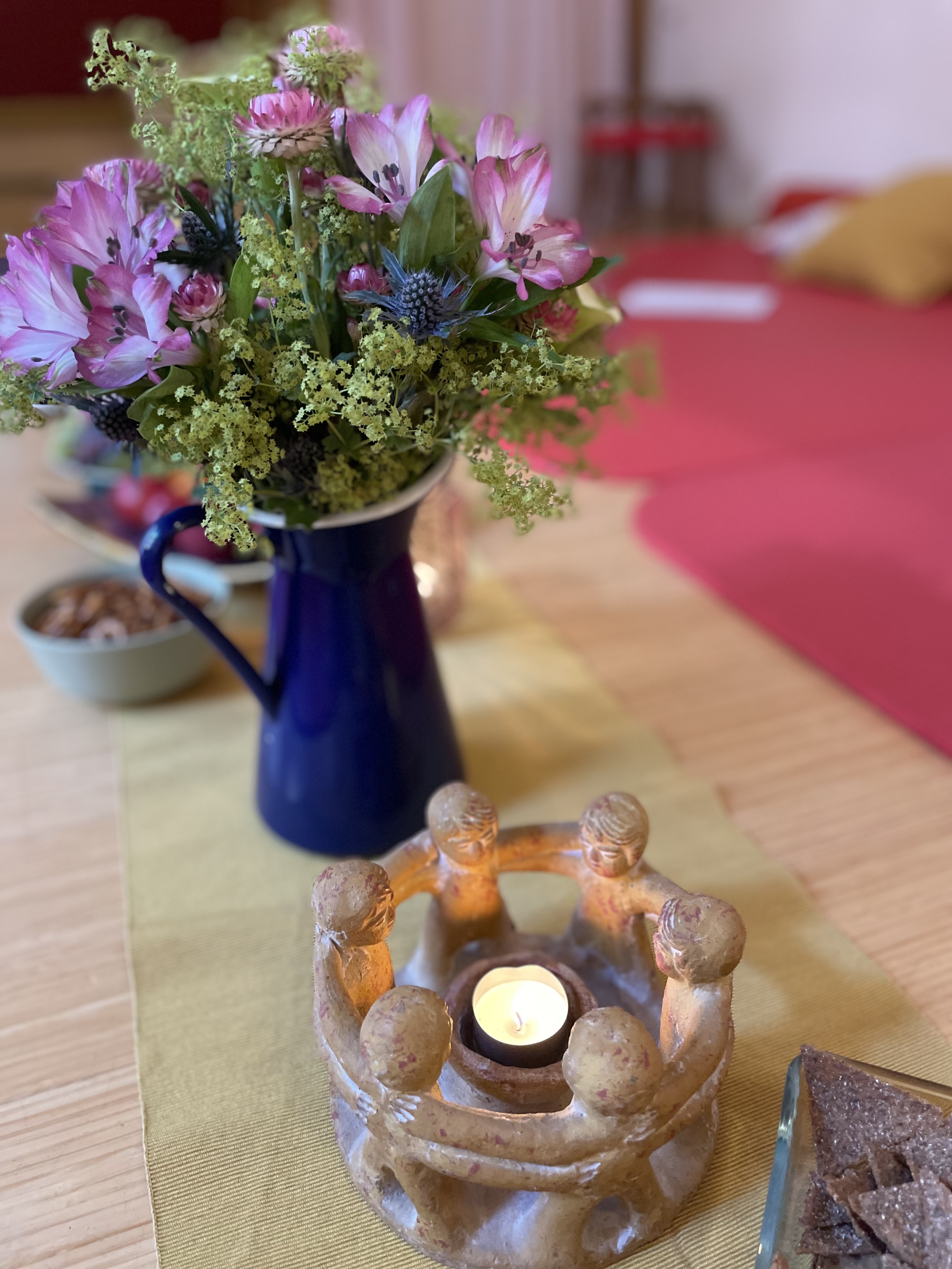 Blumenstrauß in blauer Vase mit Kerzenleuchter in Form eines Menschenkreises